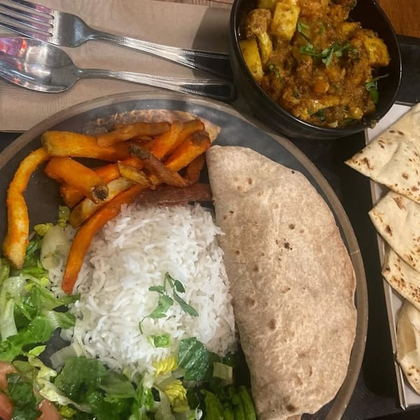 Indian meal with rice, fries, salad, flatbread, and a bowl of curry, from Hamara Restaurant.