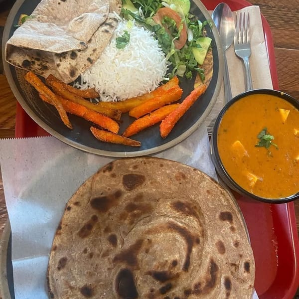 Indian meal with flatbread, rice, salad, sweet potato fries, and a bowl of paneer curry.