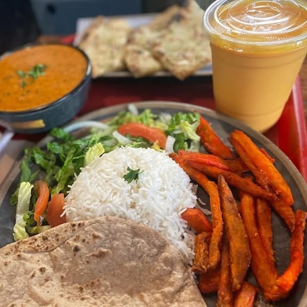 Indian meal with rice, flatbread, sweet potato fries, salad, soup, and mango lassi.